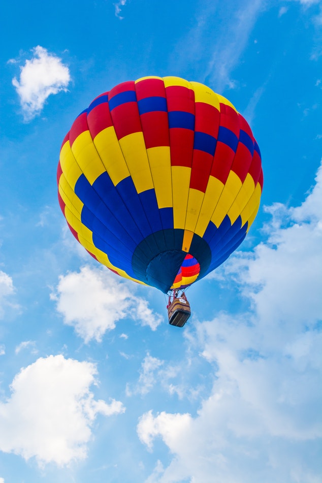 Hot air balloon way up above in flight over blue skies